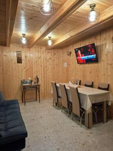 a dining room with a table and chairs and a tv at Guest House Nanu in Mestia