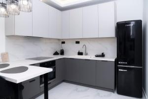 a kitchen with white cabinets and a black refrigerator at Agias Sofias Luxury Apartments in Thessaloniki