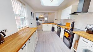 a kitchen with white cabinets and wooden counter tops at Sheringham Luxury, Cinema, Hot Tub & Beach in Sheringham