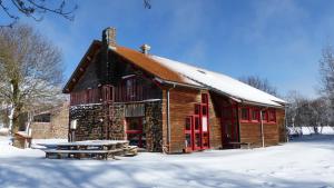 Cabaña de madera con puertas rojas en la nieve en Le Gîte du Velay en Bains