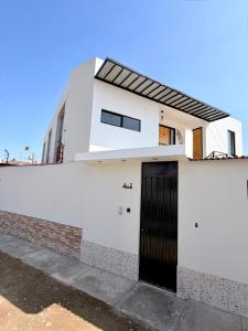 a white building with a black door on it at Dpto familiar moderno 2do piso - 2 Hab - 3 camas - wifi - lavadora in Tacna
