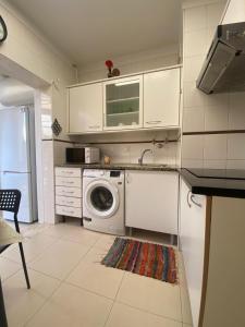 a kitchen with a washing machine and a microwave at Caparica Sol&Mar Apartment in Costa da Caparica