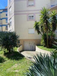 a building with palm trees in front of it at Caparica Sol&Mar Apartment in Costa da Caparica