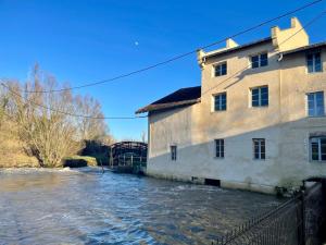 a building next to a river with water at Domaine de cézille-Appart hôtel le Moulin du lac "Paul" in Jayat +3 photos