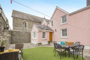 a patio with a table and chairs in front of a pink house at 3 Bed in Aberaeron oc-86578 in Aberaeron