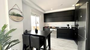 a kitchen with a black table and black cabinets at Mar, terraza y parking in Santa Pola