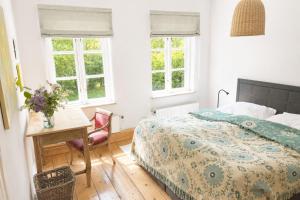 a bedroom with a bed and a desk and windows at Müllerhaus - Ostholstein in KÃ¶hn