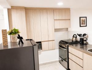 a kitchen with wooden cabinets and a stove top oven at Loft cerca a Laureles, WIFI, cerca metro, con Balcón, GUARDA MALETAS GRATIS!! in Medellín