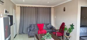 a living room with a couch and two red chairs at Simlily Place in East London +7 photos