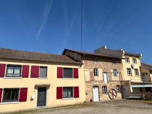 an old brick building with red shutters on it at Domaine de cézille-Appart hôtel le Moulin du lac "Paul" in Jayat