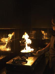 a woman standing in front of a stove with flames at YŪN Uluwatu in Uluwatu