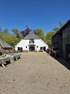 a white barn with benches in front of it at Hoeve Op Vollenhof in Wezep