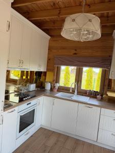 a kitchen with white cabinets and a chandelier at Luna House in Łoje +6 photos