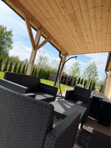 a patio with chairs and tables under a wooden roof at Luna House in Łoje