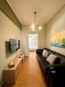 a living room with a black couch and a flat screen tv at Oscar - City Center Rooms Athens in Athens