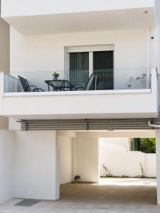 a white house with a balcony with a table and chairs at Sea & Sun Luxury Apartment in Alexandroupoli