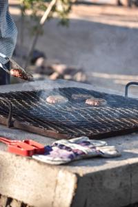 a grill with some meat and tongs on it at Kwelanga River Lodge in Vioolsdrif
