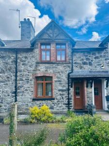an old stone house with red doors and windows at Bwythyn Ebrill, April Cottage in Betws-y-coed