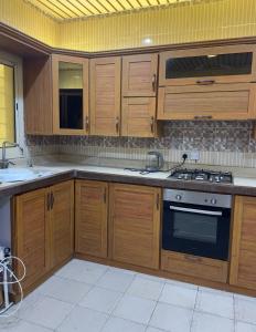 a kitchen with wooden cabinets and a stove top oven at فلة الضيافة المميزة Dhiafa Villa in Dammam