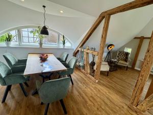 a dining room with a table and green chairs at Käpitänshaus zum Plümper in Ahrenshoop