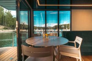 a table and chairs in a room with a view of the water at Solina Houseboat Polańczyk in Polańczyk
