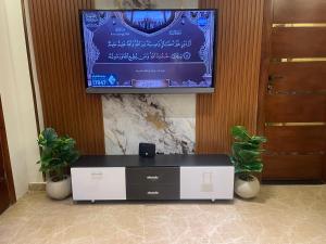 a tv on a wall in a room with plants at Leila Home Garden - Maamourah Beach in Alexandria