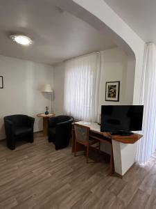 ein Wohnzimmer mit Schreibtisch, Fernseher und Stühlen in der Unterkunft Hotel Krone Riesling in Trittenheim