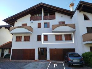 a white house with wooden doors and a car parked in front at Casa Nicole Aquileia in Aquiléia