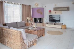 a living room with wicker furniture and a tv at Christina's Home in Skiathos