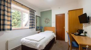 a bedroom with a bed and a desk and a window at Blaby Westfield Hotel in Blaby