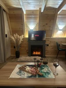 a living room with a fireplace and a table with wine glasses at Villa Tara in Žabljak