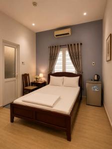 a bedroom with a large bed with a window and a table at Salyna Motel in Danang
