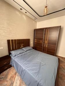 a bedroom with a large bed with a wooden headboard at Jaouhar immo in Martil