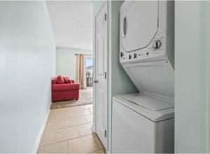 a kitchen with a washer and dryer and a red couch at MarzyMagic Oceanview's in Myrtle Beach