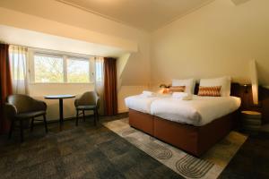 a hotel room with a bed and a table and a window at De Herbergh van Flielant in Oost-Vlieland +59 photos