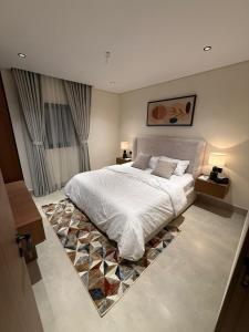 a bedroom with a large white bed with a rug at سويت إبرام- بتصميم فاخر بدخول ذاتي in Dammam