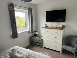 a bedroom with a dresser with a television and a chair at 22 Longstone Park in Chathill