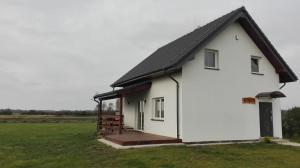 een wit huis met een zwart dak in een veld bij Dom Nad Morzem Kinga in Smołdziński Las