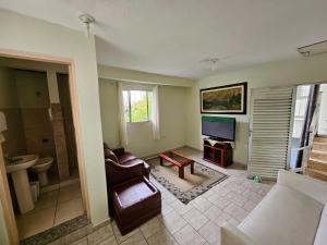 a living room with a couch and a television at Acomodação Recanto do Sameiro in Mongaguá