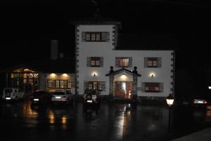 un edificio blanco con coches estacionados en un estacionamiento por la noche en La Casona de Rey, en Alvariza