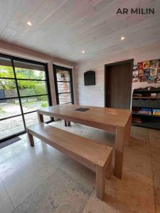 a wooden table and bench in a room with windows at Les Gîtes Ar Milin in Cordemais