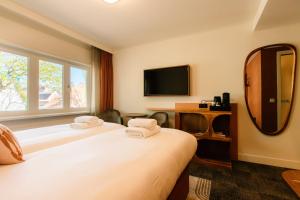 a hotel room with two beds and a mirror at De Herbergh van Flielant in Oost-Vlieland