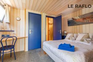 a bedroom with a bed and a blue door and a chair at Les Gîtes Ar Milin in Cordemais