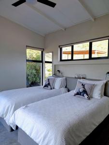 two beds in a room with two windows at Exhale Cottage in Montagu