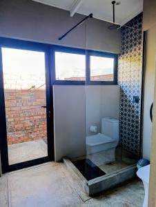 a bathroom with a glass shower with a toilet at Exhale Cottage in Montagu