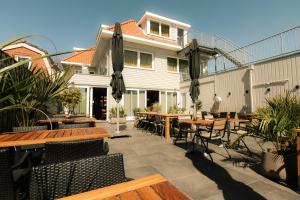 a patio with wooden tables and chairs and a house at De Herbergh van Flielant in Oost-Vlieland