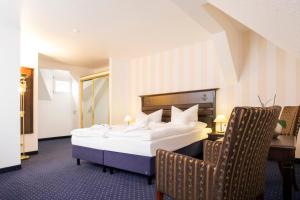 a hotel room with a large bed and two chairs at Promenadenhotel Admiral in Bansin +40 photos