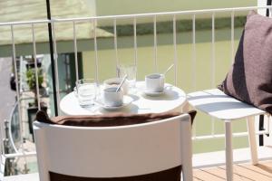 a table with two cups and glasses on a balcony at Vanity Suite in Sorrento