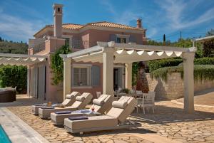 a patio with chairs and a pergola and a house at Andromeda Villa in Tranakatika