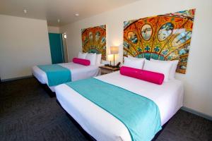 two beds in a hotel room with a painting on the wall at Carousel Beach Inn in Santa Cruz